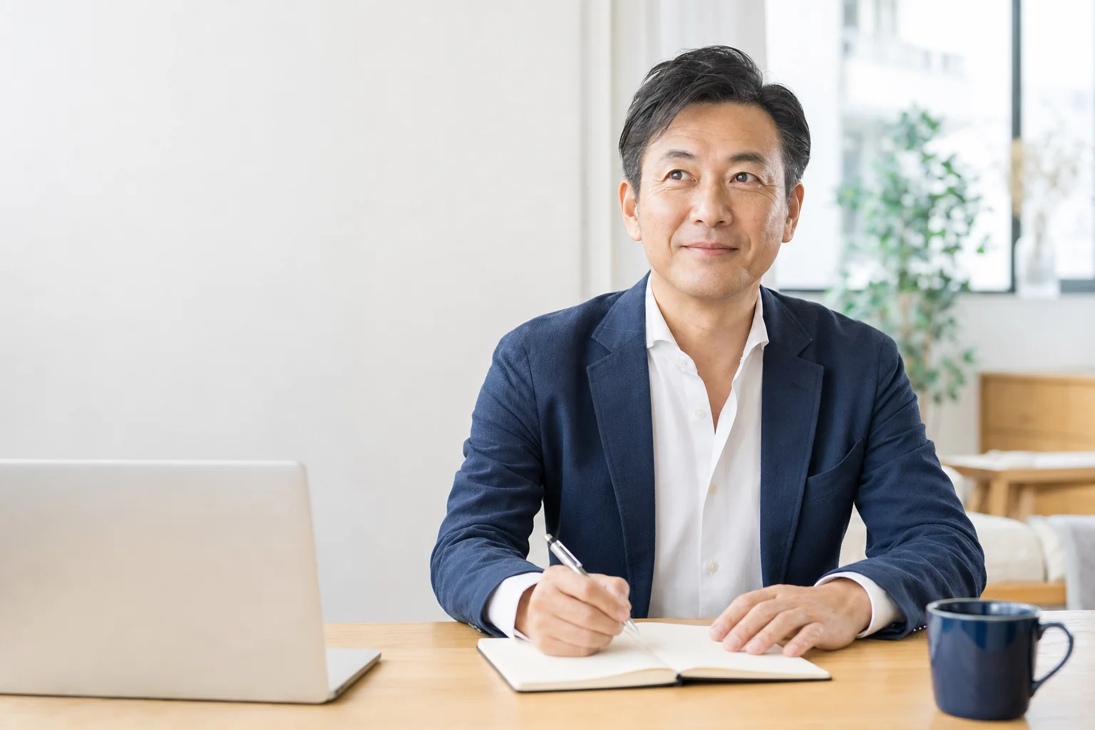 明るいオフィスでノートを取りながら考える経営者の男性