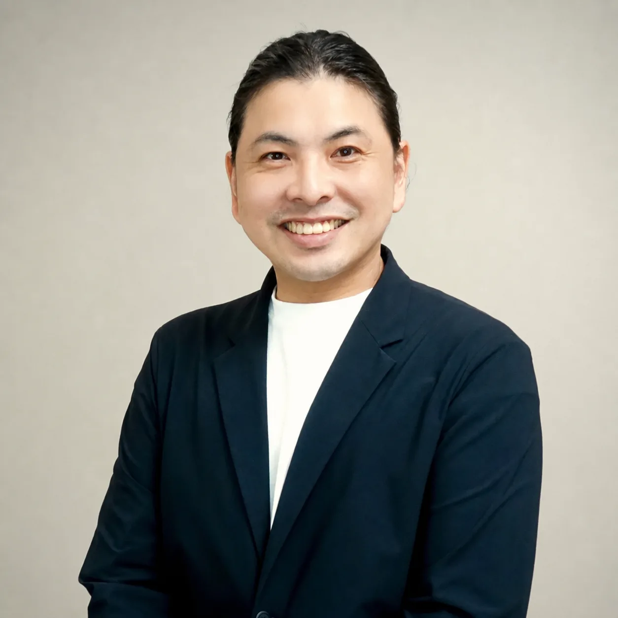 紺色のジャケットを着て微笑む講師の池田雅紀