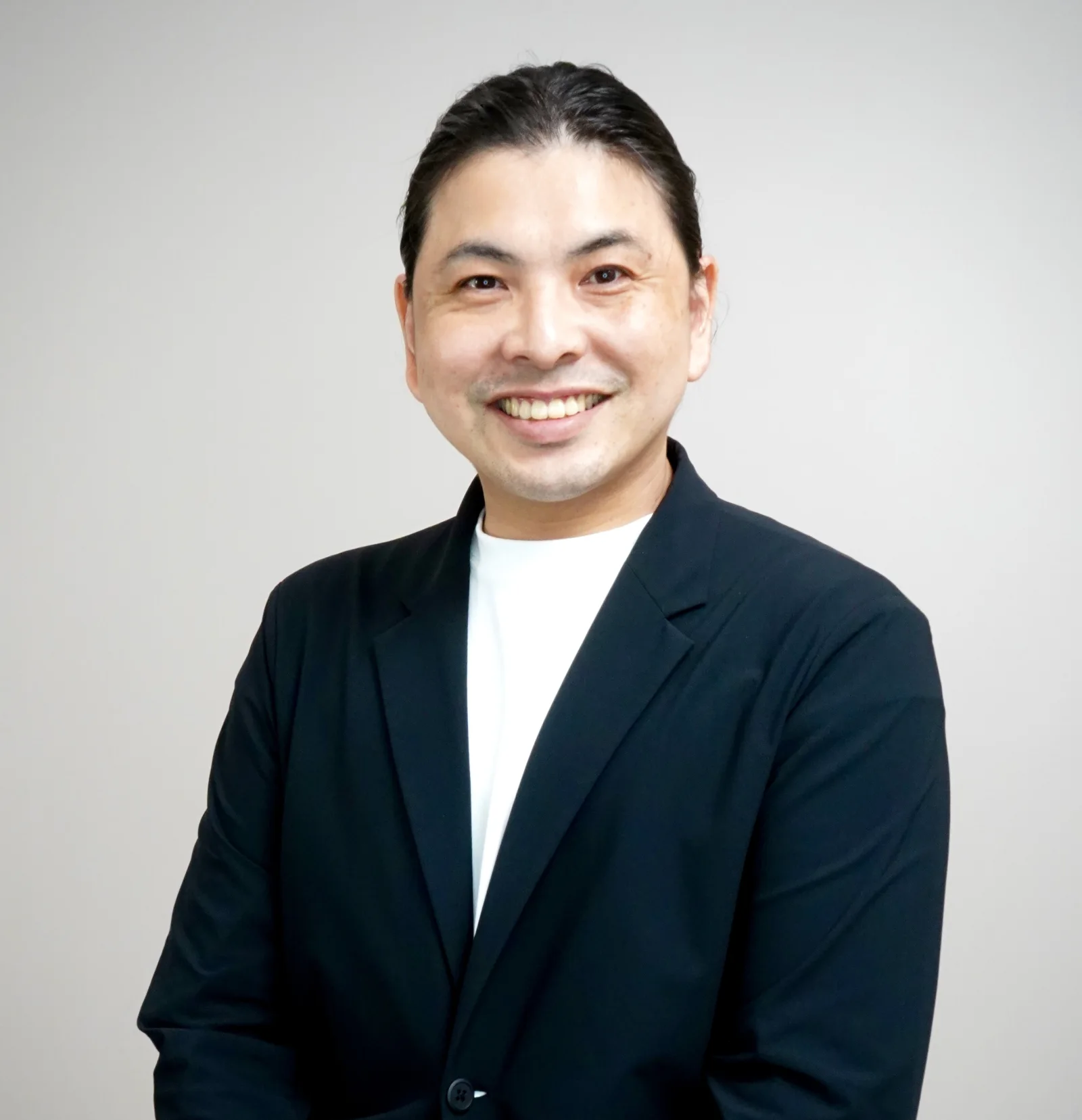 紺色のジャケットを着て微笑む講師の池田雅紀