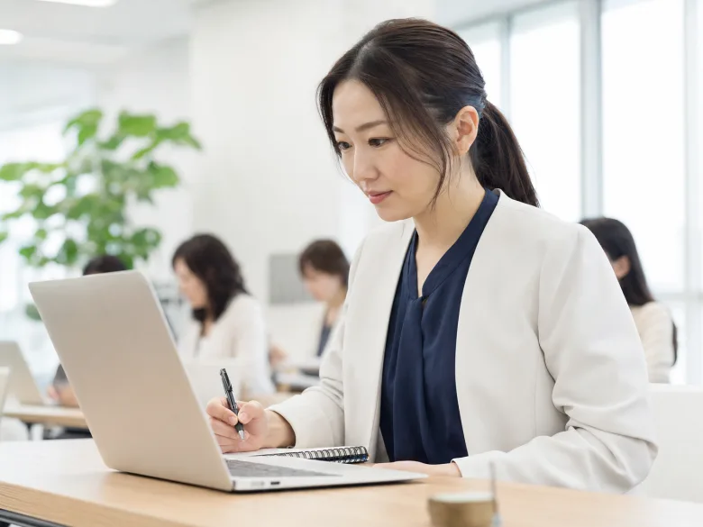 明るいセミナールームでノートPCを確認する30代の日本人女性参加者のイメージ